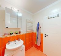 Badezimmer in einer 2-Zimmer-Wohnung mit heller Sanitärkeramik und orangefarbenen Fliesen.
