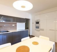 Küche in einer Einzimmerwohnung mit eleganten Schränken und einem hellen Esstisch.
