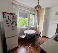 Küche in einer 2-Zimmer-Wohnung mit Holzboden, Esstisch und Kühlschrank.