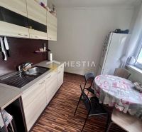 Küche in einer 2-Zimmer-Wohnung mit Holzboden und Vorhängen am Fenster.
