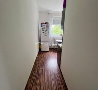 Ein schmaler Flur mit Holzboden führt in die Küche einer Zweizimmerwohnung.