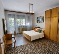 Ein Schlafzimmer in einem Einfamilienhaus mit Teppichboden, einem Bett und Holzmöbeln.