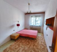 Schlafzimmer im Einfamilienhaus mit Bett, Teppich und Fenster mit weißem Vorhang.