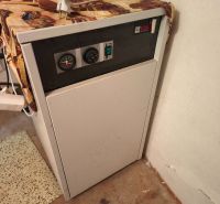 Kessel im Inneren eines Einfamilienhauses mit Bedienfeld und orangefarbenem Behälter oben drauf.