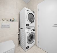 Waschmaschine mit Trockner im Badezimmer einer 2-Zimmer-Wohnung, helle Fliesen und Toilette.