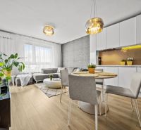 Wohnzimmer in einer 2-Zimmer-Wohnung mit Holzboden, hellen Möbeln und Pflanzen.
