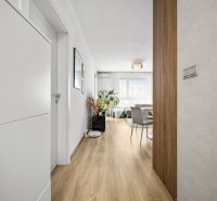 Ein Flur mit einem Holzboden, der in das Wohnzimmer einer Zweizimmerwohnung führt.