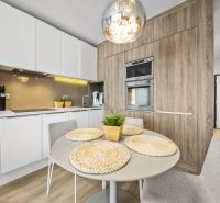 Küche in einer 2-Zimmer-Wohnung mit Holzboden, Tisch und eingebauten Geräten.