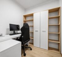 Ein Arbeitsbereich mit Computer, Drucker und Regalen in einer 2-Zimmer-Wohnung mit einem Holzboden.