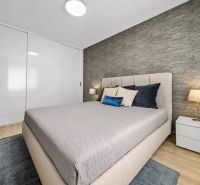 Schlafzimmer in einer 2-Zimmer-Wohnung mit Bett, Nachttischen und Boden mit Holzdekor.