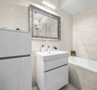 Badezimmer mit Spiegel, Waschbecken und Badewanne in einer 2-Zimmer-Wohnung; sauberes und helles Design.