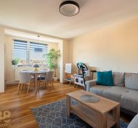 Wohnzimmer mit Sofa und Esstisch, Boden mit Holzdekor.