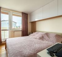 Schlafzimmer mit rosa Überdecke in einer 3-Zimmer-Wohnung, ausgestattet mit einem Boden in Holzoptik.