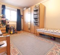 Schlafzimmer mit großem Bett, Schrank, Teppich und Holzboden in einer 2-Zimmer-Wohnung.