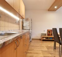 Küche in einer 2-Zimmer-Wohnung mit Holzboden und Holzschränken.