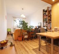 Wohnzimmer mit Holzdekorboden, Sofa, Tisch und Bücherregal in einer Zweizimmerwohnung.