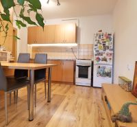 Küche in einer 2-Zimmer-Wohnung mit Holzboden, Esstisch und Kühlschrank.