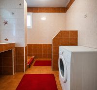 Badezimmer in einem Einfamilienhaus mit Dusche und Waschmaschine, Fliesen in Brauntönen.