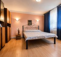 Schlafzimmer mit einem Metallbett, Holzboden, Möbel und Vorhänge in einem Einfamilienhaus.