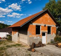 Ein Einfamilienhaus in Šalgočka mit einer unverputzten Ziegelfassade und einem schrägen Dach.