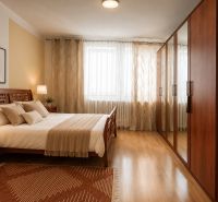 Schlafzimmer im Einfamilienhaus mit Holzmöbeln und Bodenbelag in Holzoptik.