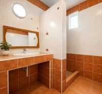 Ein Badezimmer in einem Einfamilienhaus mit Keramikfliesen und einem Holzspiegel.