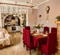 Esszimmer in einem Einfamilienhaus mit roter Tischdecke, Küche und Dekoration mit einer antiken Wanduhr.