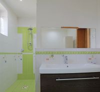 Badezimmer mit Dusche und grünen Fliesen in einem Einfamilienhaus.