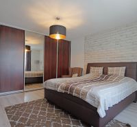 Schlafzimmer in einem Einfamilienhaus mit Bett, Holzschränken und weißer Steinwand.