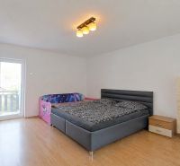 Ein Schlafzimmer in einem Einfamilienhaus mit einem Bett, einem Kinderbett und einem Boden mit Holzdekor.