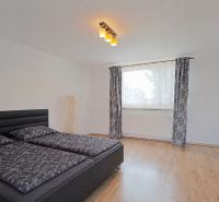 Schlafzimmer in einem Einfamilienhaus mit Bett und Boden in Holzoptik.