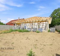 Ein im Bau befindliches Einfamilienhaus in Marcelová mit Umzäunung, stehend auf einem leeren Grundstück mit Rasen.