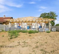 Der Bau eines Einfamilienhauses in Marcelová mit einem im Bau befindlichen Dach und einer Umzäunung.