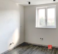 Einfaches Zimmer in einer Einzimmerwohnung mit Holzboden und weißen Wänden.