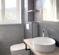 Badezimmer in einer Einzimmerwohnung mit Waschbecken und Boden in Holzoptik.