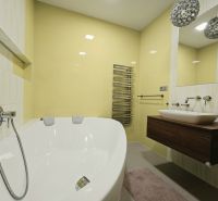 Badezimmer mit Badewanne in einer 4-Zimmer-Wohnung, mit gelben Fliesen und modernem Waschbecken.