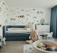 Kinderzimmer mit Spielzeug, blauem Bett, Tapete mit Autos und Boden mit Holzdekor.