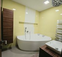 Ein Badezimmer mit gelben Fliesen, einer Eckbadewanne und einem Holzdekor am Schrank in einer 4-Zimmer-Wohnung.