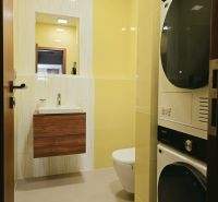 Badezimmer in einer 4-Zimmer-Wohnung, hellgelbe Fliesen, Waschbecken, Toilette, Waschmaschine und Trockner.