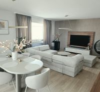 Ein stilvolles Wohnzimmer mit einem bequemen Sofa, einem Esstisch und einem Holzboden in einer 4-Zimmer-Wohnung.