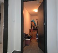 Flur mit grauen Fliesen und einem Abstellraum in einer 4-Zimmer-Wohnung.