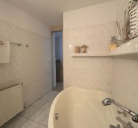 Badezimmer in einer Einzimmerwohnung mit Badewanne, Keramikfliesen und Dekorationen.