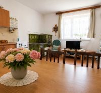 Küche in einem Einfamilienhaus mit Kachelherd, Esstisch und Blumendekoration.