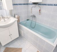 Badezimmer mit weißem Waschtischunterschrank und blauer Badewanne in einem Einfamilienhaus.