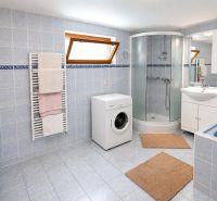 Badezimmer in einem Einfamilienhaus mit Badewanne, Dusche und Waschmaschine.