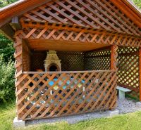 Pavillon mit Holzgittern und Außengrill im Garten bei einem Einfamilienhaus.