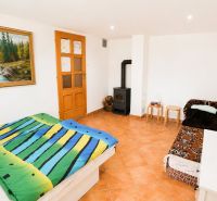 Schlafzimmer mit bunter Bettwäsche, Sofa, Kamin und Bild in einem Einfamilienhaus.