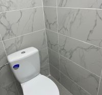 Toilette mit Marmorverkleidung in Geschäftsräumen, grauer Boden.
