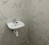 Waschbecken und Fliesen in Geschäftsräumen mit Marmoroptik.