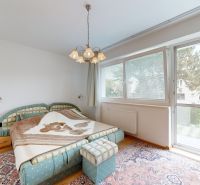 Schlafzimmer in einer 3-Zimmer-Wohnung mit großem Fenster, buntem Teppich und Doppelbett.